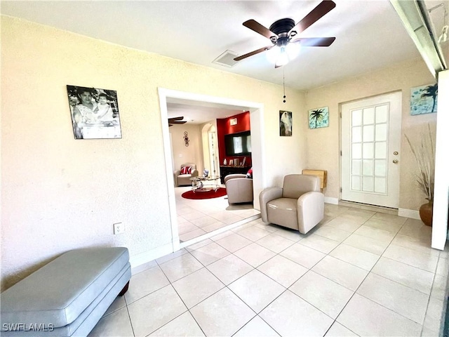 living area with light tile patterned floors, ceiling fan, and baseboards