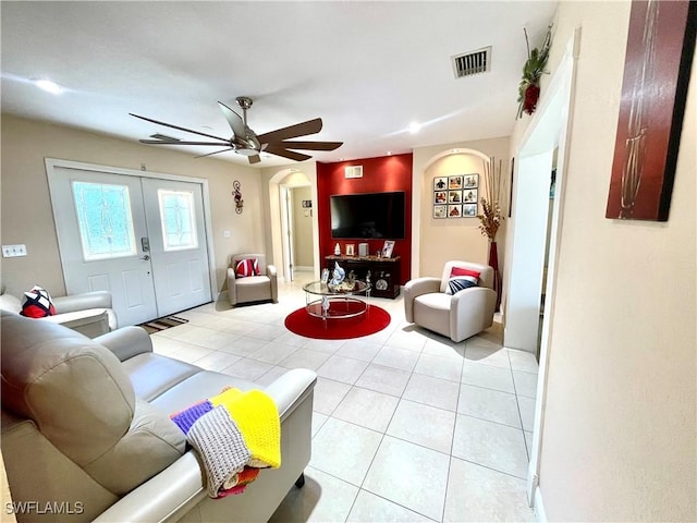 living room with arched walkways, french doors, visible vents, light tile patterned flooring, and ceiling fan