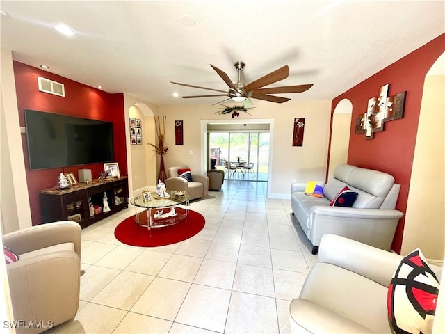 living area featuring arched walkways, visible vents, ceiling fan, and light tile patterned flooring