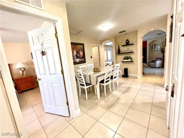 dining space featuring arched walkways, visible vents, baseboards, and light tile patterned floors