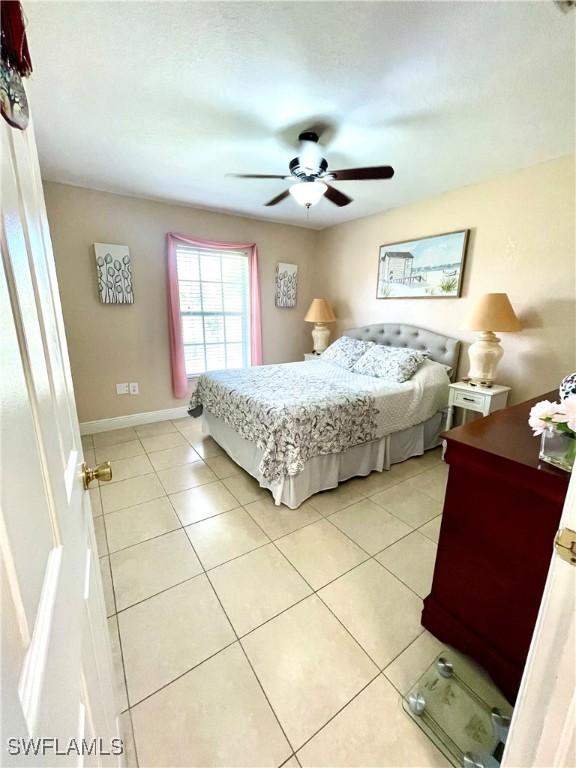 bedroom with light tile patterned floors, ceiling fan, and baseboards