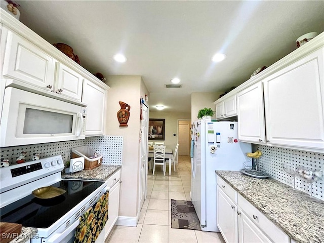 kitchen with white appliances, white cabinetry, and visible vents