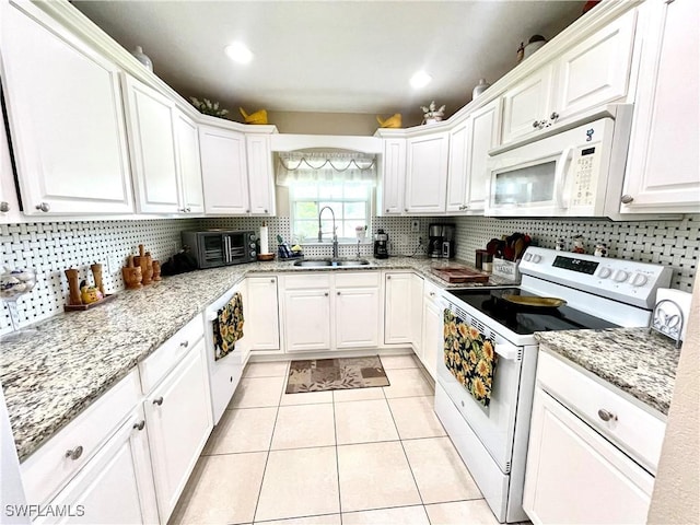 kitchen featuring light tile patterned flooring, white appliances, a sink, white cabinets, and tasteful backsplash