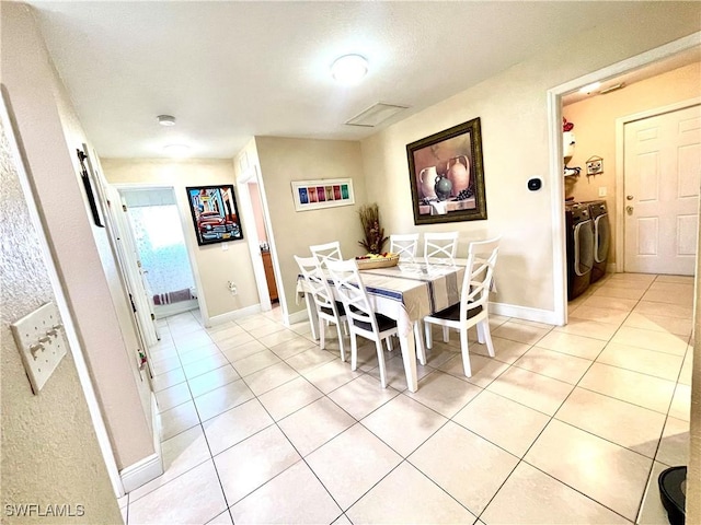 dining room featuring separate washer and dryer, light tile patterned flooring, and baseboards