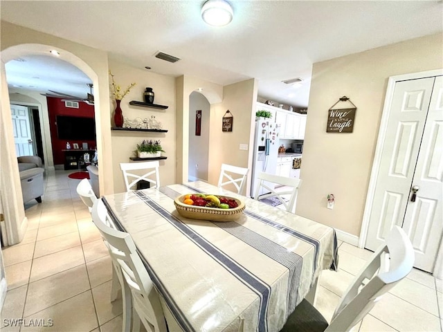 dining room featuring light tile patterned floors, visible vents, arched walkways, and baseboards