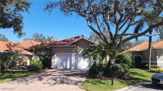 view of front of house with a garage, a tile roof, decorative driveway, and stucco siding