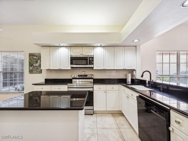 kitchen with stainless steel appliances, recessed lighting, white cabinetry, a sink, and dark stone countertops