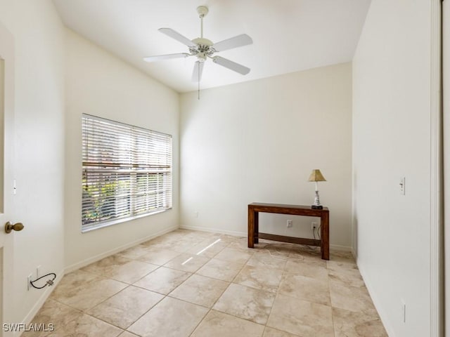 empty room with light tile patterned flooring, a ceiling fan, and baseboards