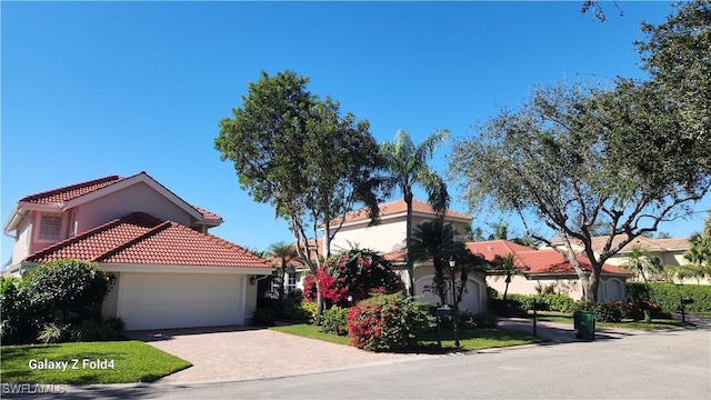 mediterranean / spanish-style home featuring a garage, stucco siding, driveway, and a tiled roof