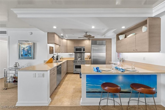 kitchen featuring a peninsula, light countertops, premium appliances, and a kitchen breakfast bar