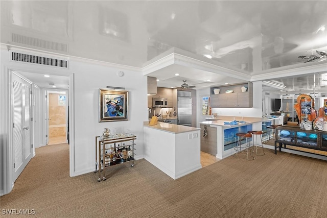 kitchen with a breakfast bar, stainless steel appliances, visible vents, light countertops, and a peninsula