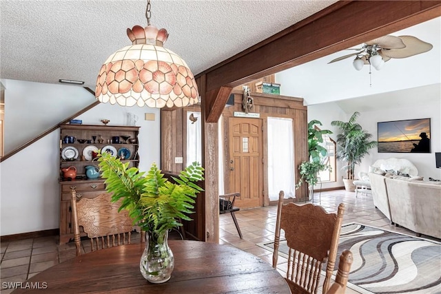 dining room with a textured ceiling, light tile patterned flooring, a ceiling fan, baseboards, and beam ceiling