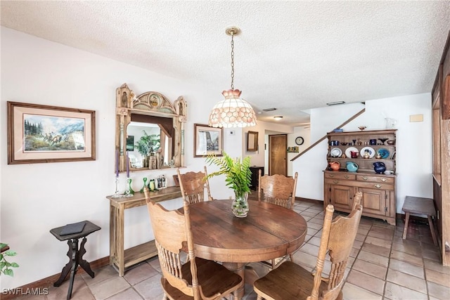 dining space featuring a textured ceiling, light tile patterned flooring, and baseboards