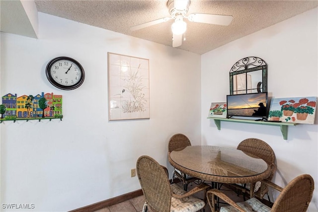 tiled dining space with baseboards, a ceiling fan, and a textured ceiling