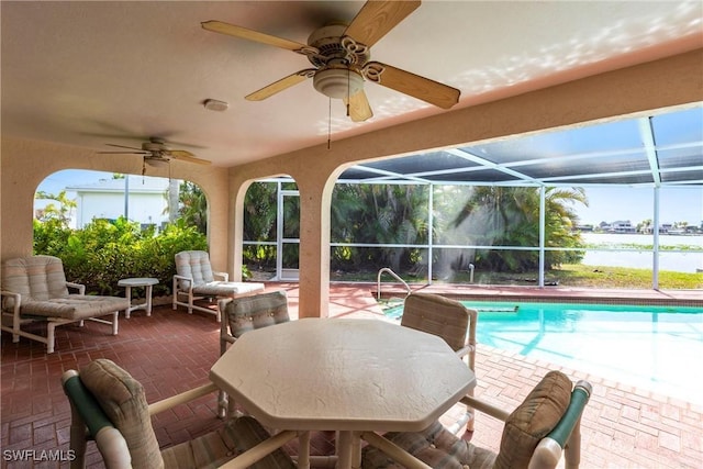 exterior space featuring glass enclosure, a water view, a ceiling fan, and an outdoor pool