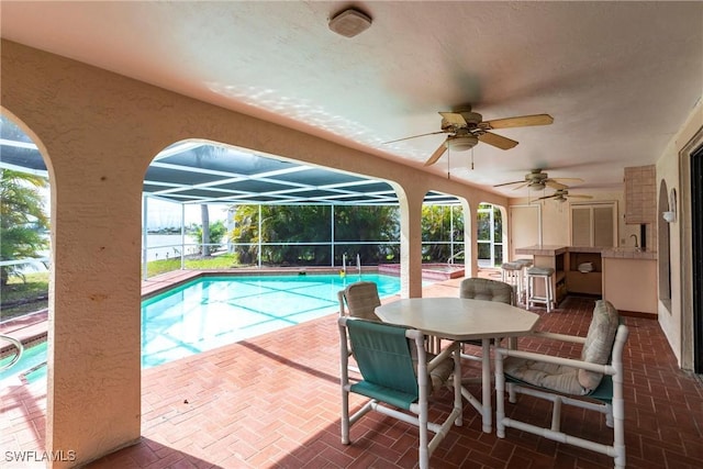 outdoor pool featuring a lanai, a patio area, a ceiling fan, and outdoor dining space