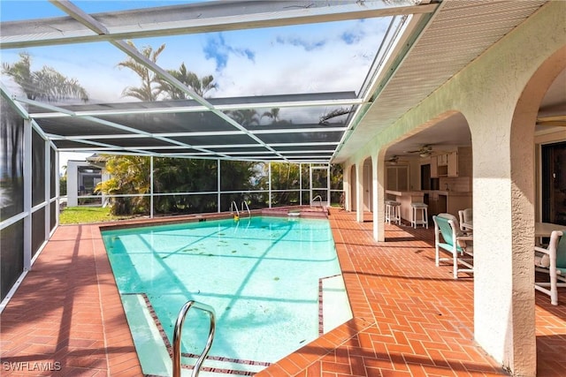 pool featuring a ceiling fan, glass enclosure, and a patio area