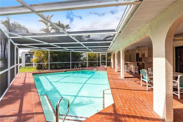 pool featuring glass enclosure, ceiling fan, and a patio