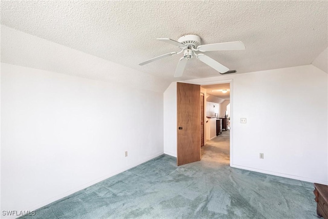 interior space with ceiling fan, vaulted ceiling, a textured ceiling, and carpet flooring