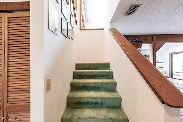 staircase featuring a textured ceiling and visible vents