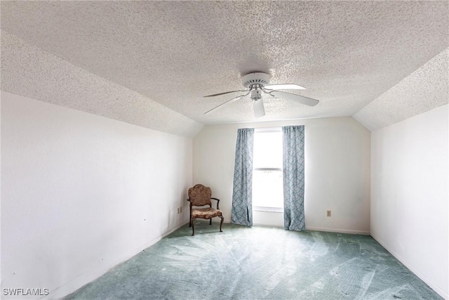 unfurnished room with carpet floors, vaulted ceiling, a textured ceiling, and a ceiling fan