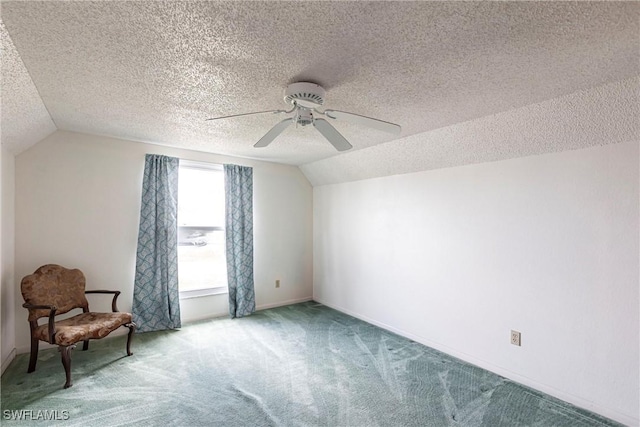 interior space with a ceiling fan, carpet, lofted ceiling, and a textured ceiling