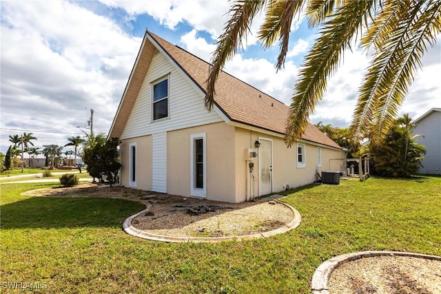 view of home's exterior featuring a shingled roof, cooling unit, a yard, and stucco siding