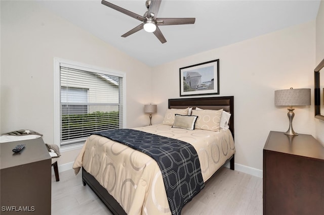 bedroom featuring vaulted ceiling, light wood-style flooring, and baseboards