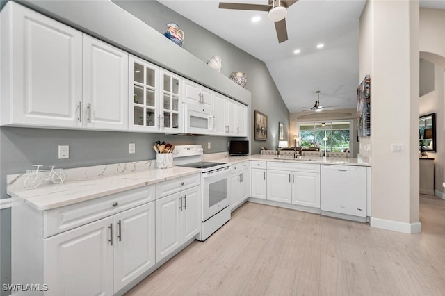 kitchen featuring white appliances, glass insert cabinets, light stone countertops, white cabinetry, and a sink