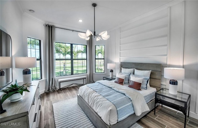 bedroom featuring multiple windows, crown molding, an inviting chandelier, and wood finished floors