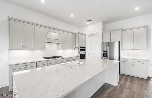 18372 Ridgeline Dr, Estero, FL 33928 - kitchen featuring visible vents, an island with sink, custom range hood, appliances with stainless steel finishes, and a sink
