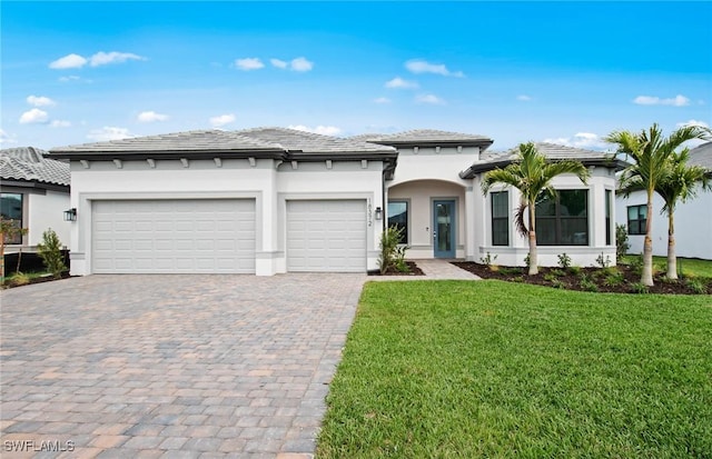 prairie-style house featuring decorative driveway, an attached garage, stucco siding, and a front yard