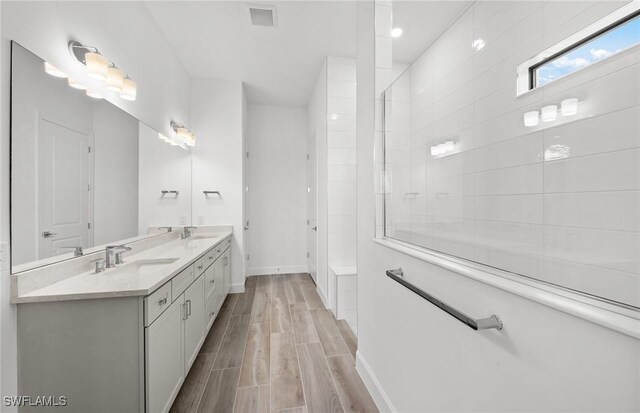 18372 Ridgeline Dr, Estero, FL 33928 - bathroom featuring wood finish floors, double vanity, visible vents, a sink, and a walk in shower