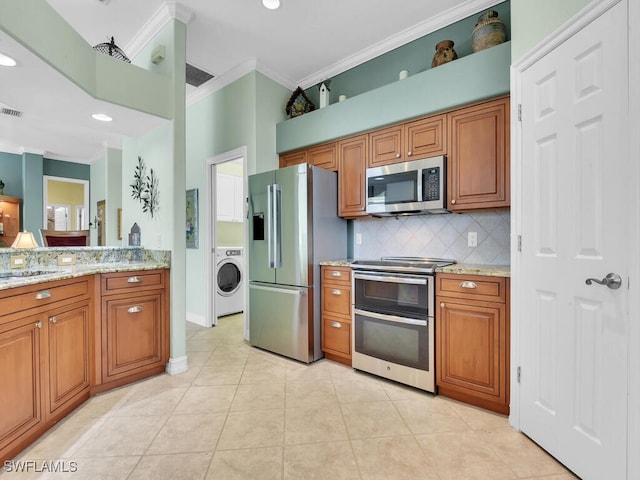 kitchen with stainless steel appliances, washer / clothes dryer, decorative backsplash, brown cabinetry, and ornamental molding