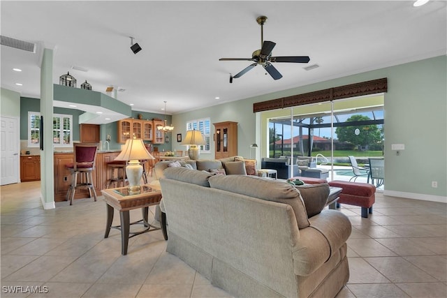 living room with light tile patterned floors, baseboards, visible vents, and ceiling fan with notable chandelier