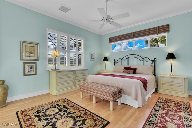 bedroom featuring visible vents, baseboards, a ceiling fan, ornamental molding, and light wood-type flooring