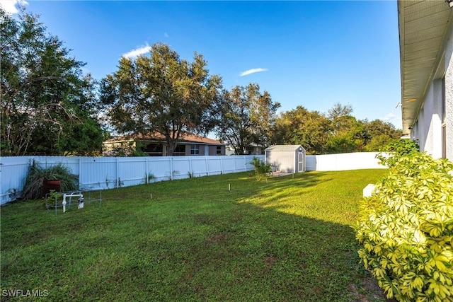 view of yard with a storage shed, an outbuilding, and a fenced backyard