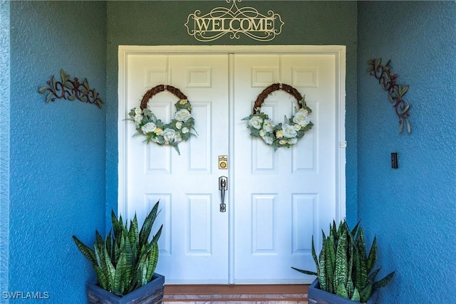 doorway to property featuring stucco siding