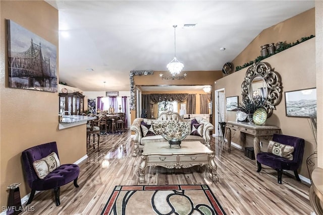 living area with vaulted ceiling, wood finished floors, visible vents, and baseboards