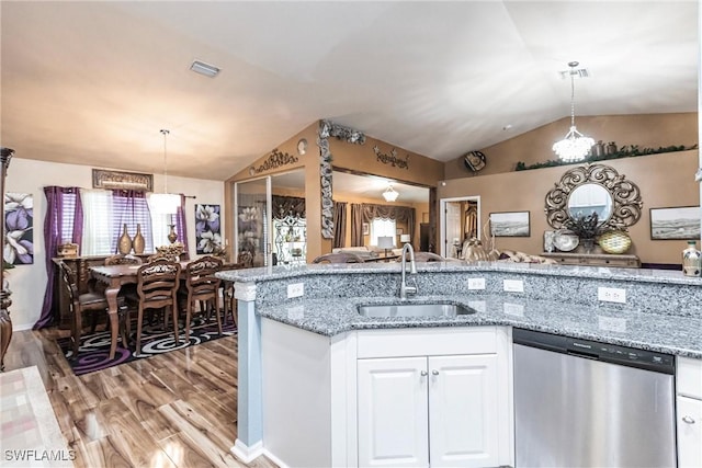 kitchen featuring pendant lighting, open floor plan, white cabinetry, a sink, and dishwasher