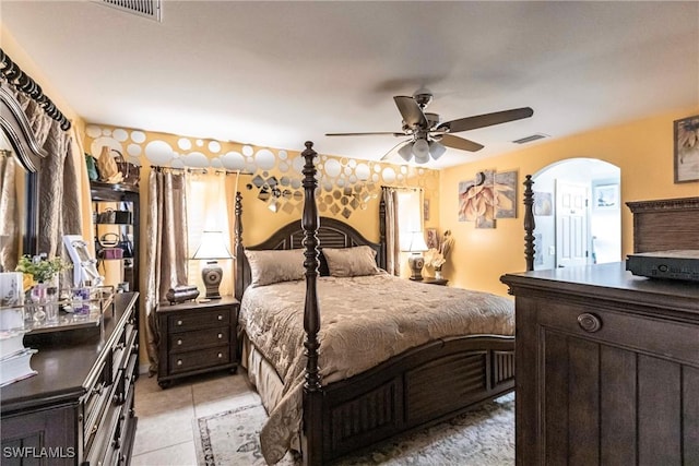 bedroom featuring a ceiling fan, arched walkways, visible vents, and light tile patterned floors