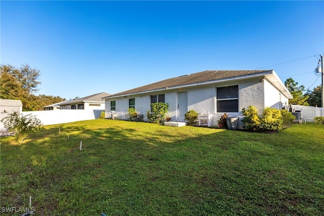 back of house with a lawn, fence, and stucco siding