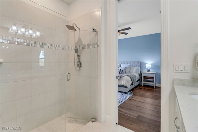 ensuite bathroom with ensuite bathroom, ceiling fan, wood finished floors, vanity, and a stall shower