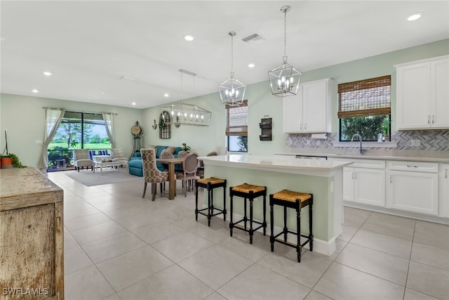 kitchen featuring open floor plan, light countertops, a kitchen island, and white cabinets