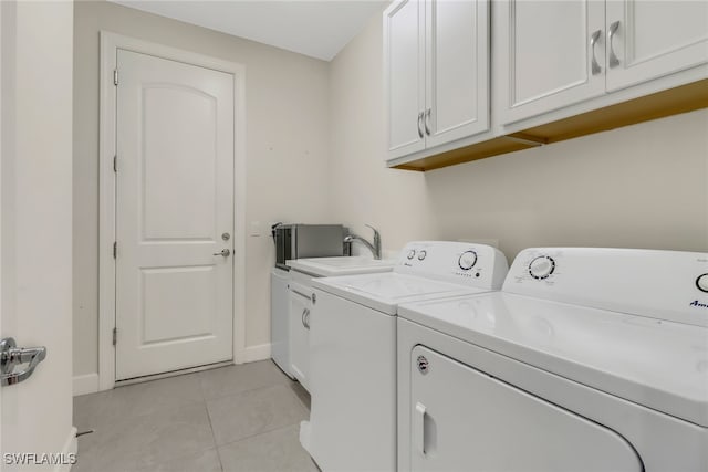 laundry room featuring cabinet space, light tile patterned floors, baseboards, and separate washer and dryer