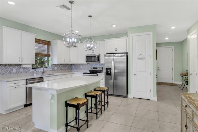 kitchen featuring white cabinetry, stainless steel appliances, light countertops, and a center island