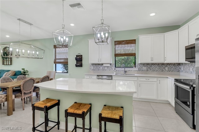 kitchen with stainless steel appliances, white cabinets, light countertops, and a kitchen island