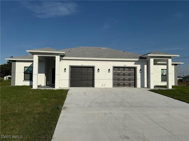 prairie-style house featuring a garage, a shingled roof, concrete driveway, stucco siding, and a front yard