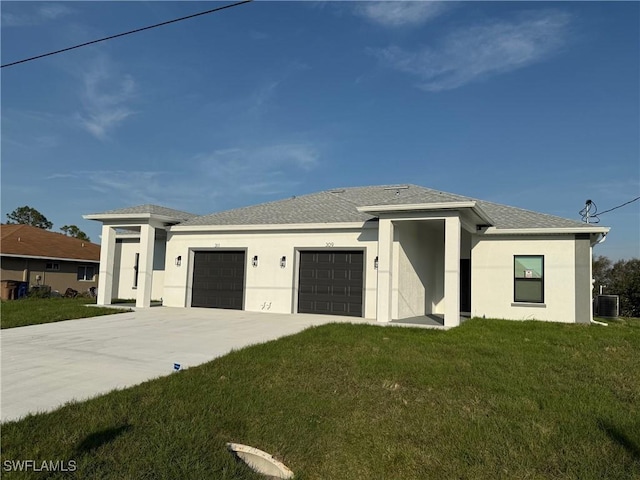 prairie-style home featuring a garage, stucco siding, concrete driveway, and a front yard