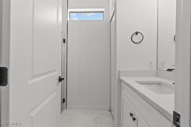 bathroom with marble finish floor, walk in shower, vanity, and baseboards